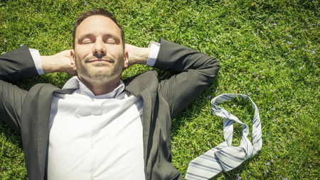 Smiling businessman lying on grass